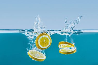 lemon slices falling into water with splashes
