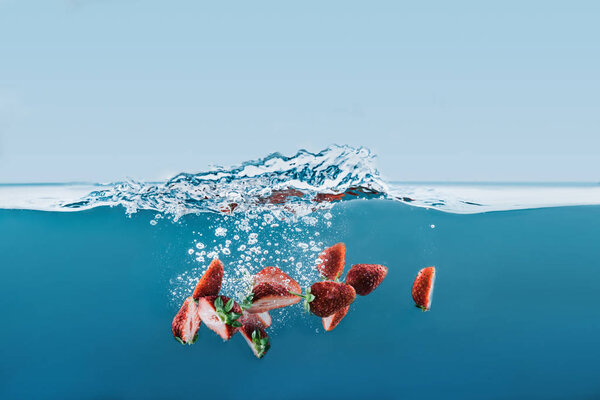 pieces of strawberries falling into water with splashes