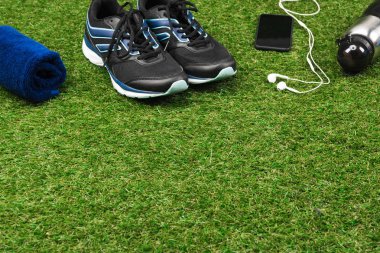 trainers with smartphone and sport bottle on grass clipart