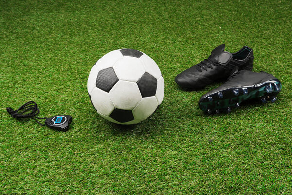 stopwatch with soccer ball and boots on grass