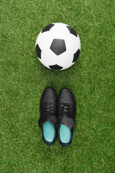 Bola de futebol com botas pretas — Fotografia de Stock