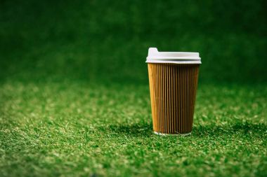 disposable cup of coffee on green lawn clipart