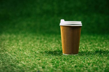 disposable cup of coffee on green lawn clipart