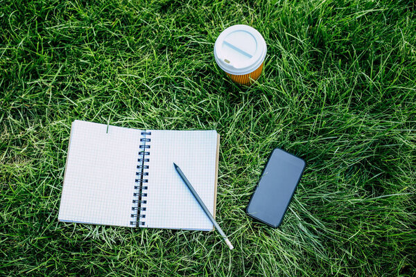 Notebook and digital device on grass 