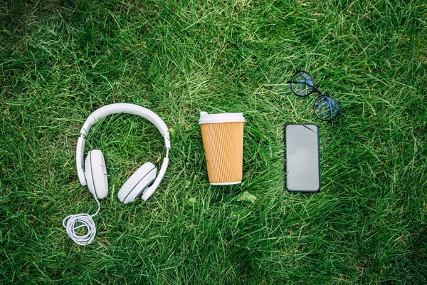 Digitale apparaten en papier cup op gras — Stockfoto