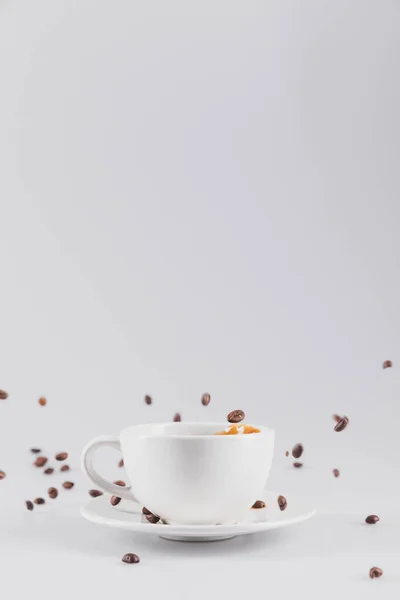 Xícara de café com grãos de café espalhados — Fotografia de Stock