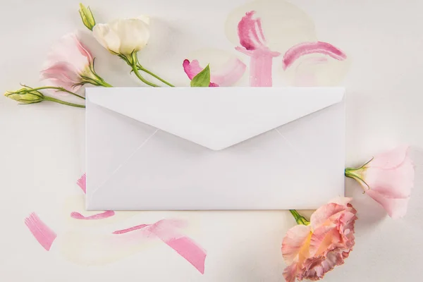 Beautiful flowers and white envelope — Stock Photo, Image