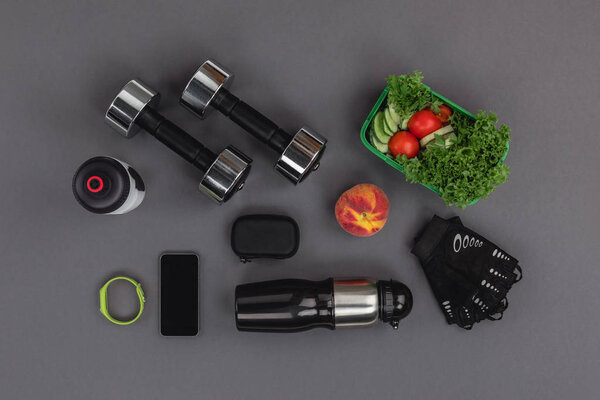 Dumbbells with vegetable salad and gadgets