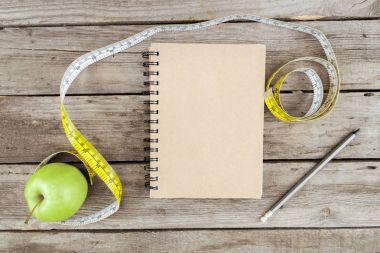 defter, taze elma ve ölçüm bandı