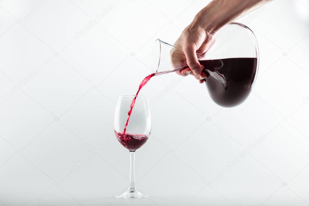 hand pouring red wine