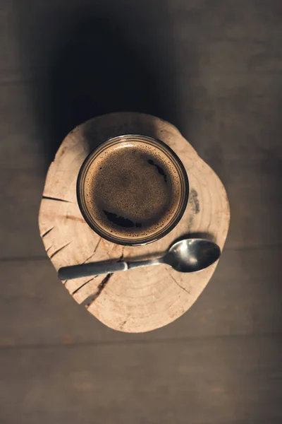 Glass of coffee and spoon on wood — Stock Photo, Image