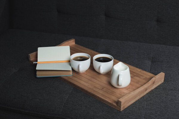 coffee, jug of milk and notebook on tray