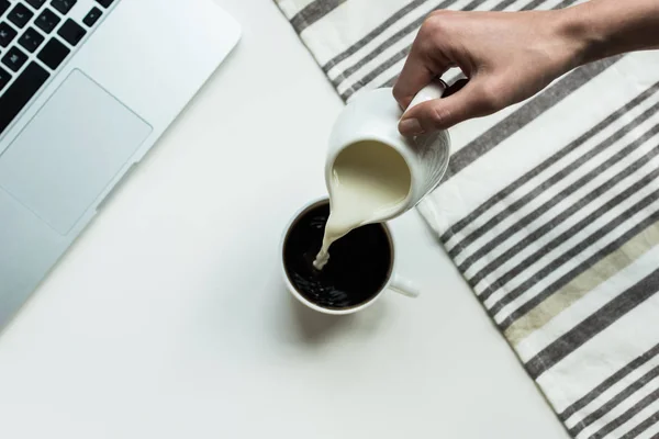 Derramando leite em xícara de café preto — Fotografia de Stock