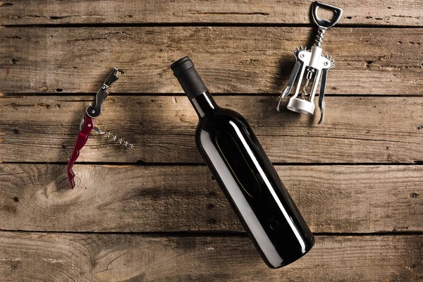 Bottle of red wine and corkscrews — Stock Photo, Image