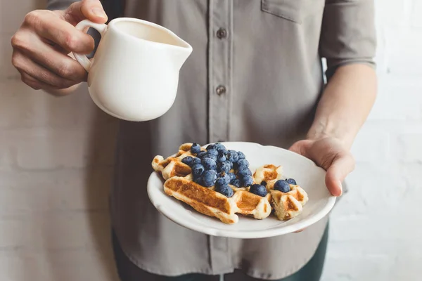 Woman pouring syrup on tasty waffles — Stock Photo, Image