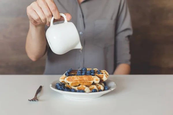 Woman pouring syrup on tasty waffles — Stock Photo, Image