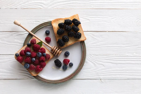 Breakfast with berries on toasts and honey — Stock Photo, Image