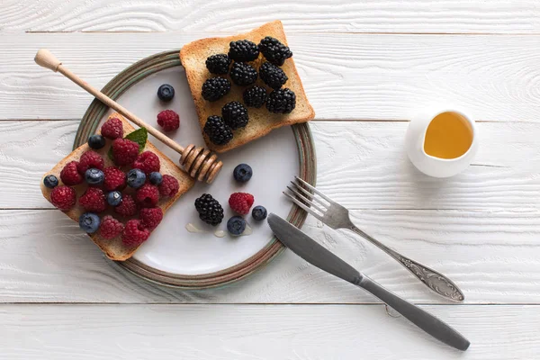 Breakfast with berries on toasts and honey — Stock Photo, Image