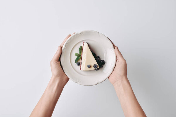 woman holding slice of cheesecake