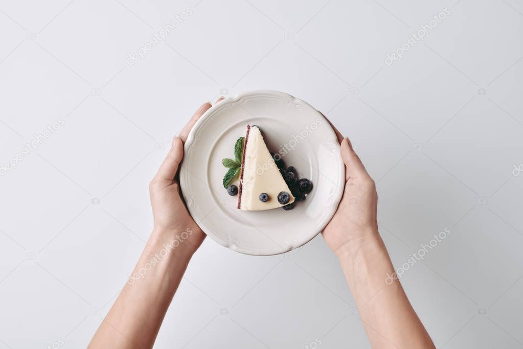 woman holding slice of cheesecake