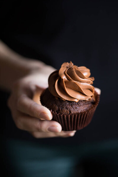 hand with chocolate cupcake