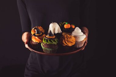 Cadılar Bayramı cupcakes tutan kişi 