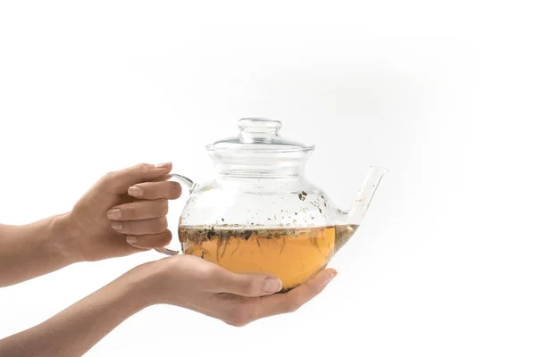 Glass teapot with herbal tea in hands — Stock Photo, Image