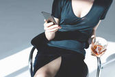 žena s smartphone a sklenicí whisky