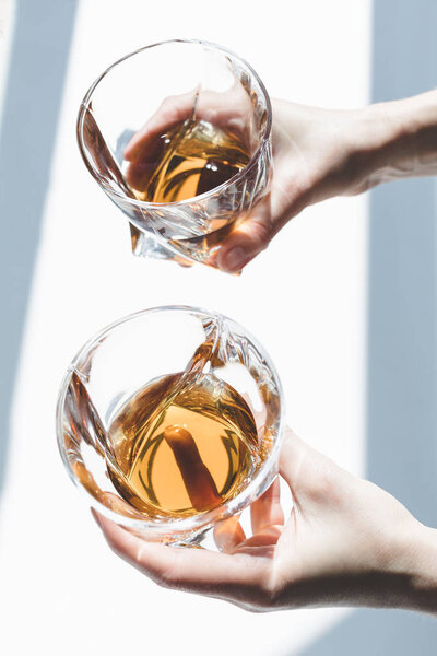 person holding glasses of whiskey  