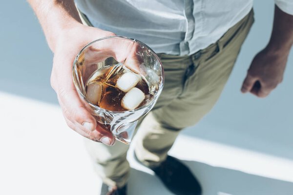 man holding whiskey with ice