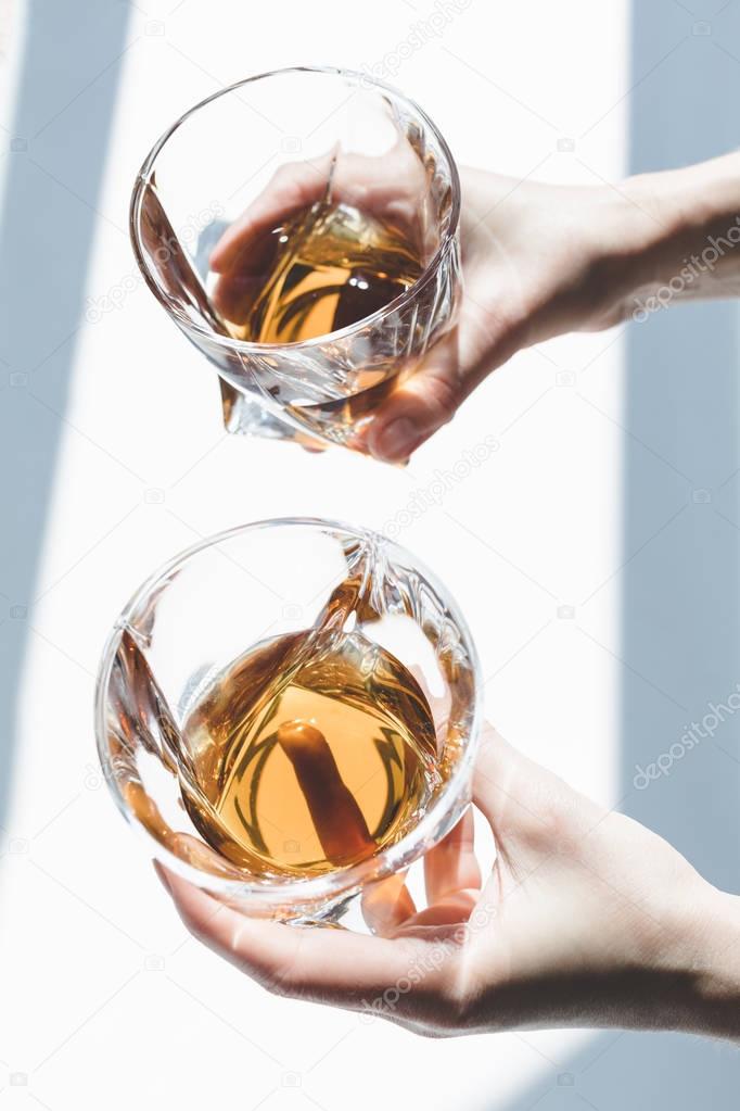 person holding glasses of whiskey  