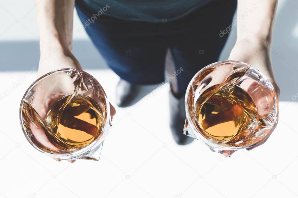 person holding glasses of whiskey 