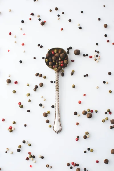 Colher com grãos de pimenta derramados — Fotografia de Stock