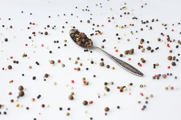 Colher com grãos de pimenta derramados — Fotografia de Stock