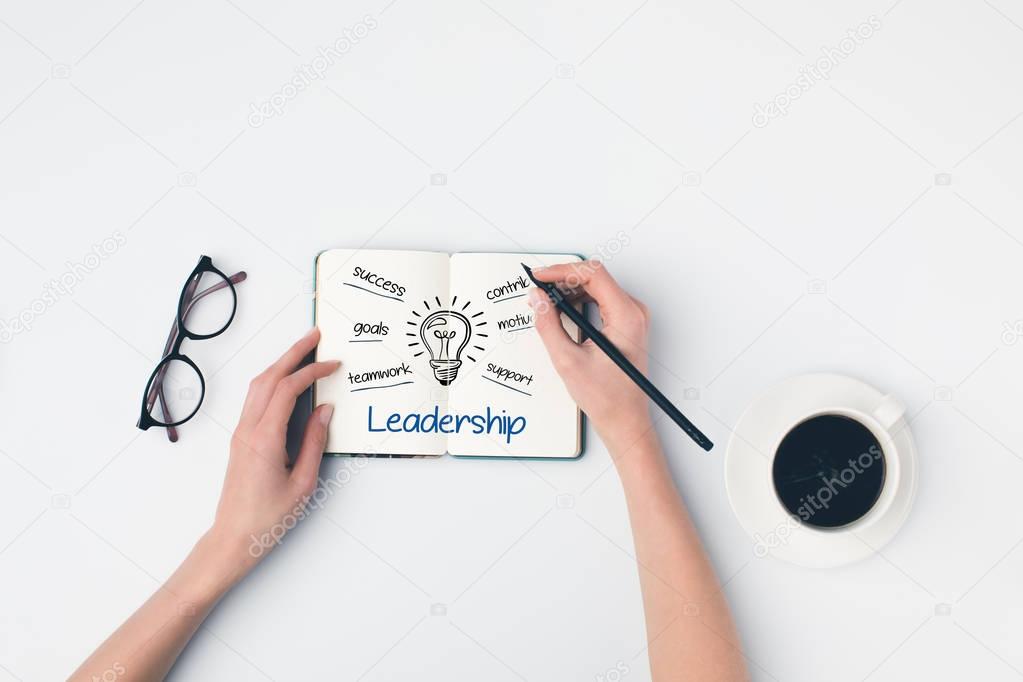 writing leadership ideas in notebook