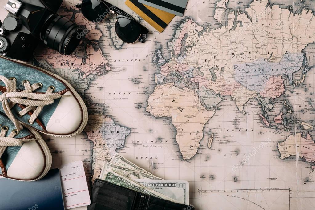 Film camera with wallet and money, shoes and passport on a big map