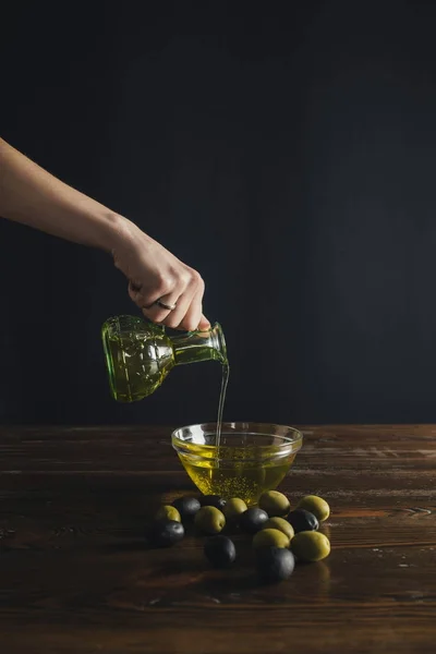 Wanita menuangkan minyak dari botol ke mangkuk — Stok Foto