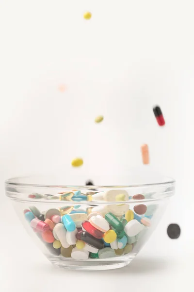 Píldoras que caen en un recipiente de vidrio — Foto de Stock