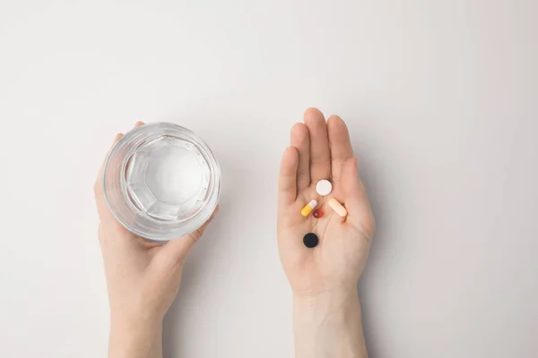 Mujer sosteniendo píldoras y vaso de agua — Foto de Stock