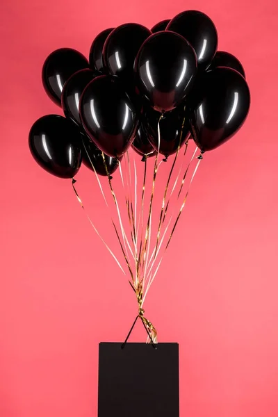 Shopping bag hanging on black balloons — Stock Photo, Image