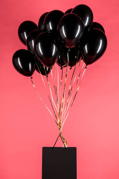 сумка висит на черных воздушных шарах
