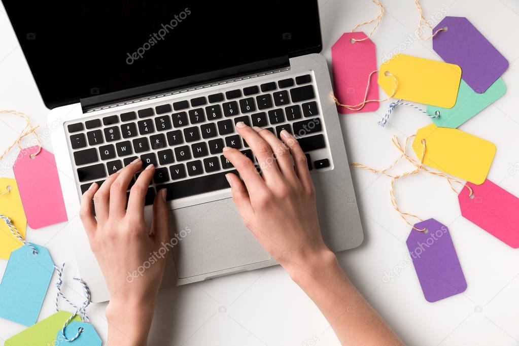 Cropped shot of woman typing on laptop with blank labels near by isolated on white