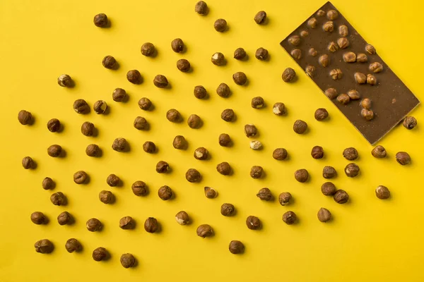 Chocolate bar with scattered nuts — Stock Photo, Image