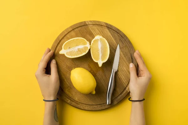 Woman holding wooden board with lemons — Stock Photo, Image