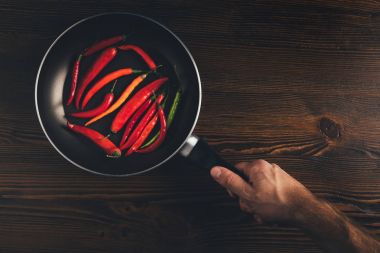 man holding pan with chili peppers clipart
