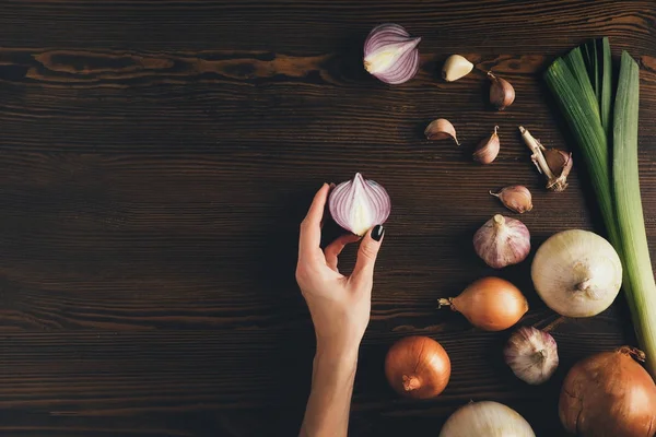 Frau hält halbe Zwiebel in der Hand — Stockfoto