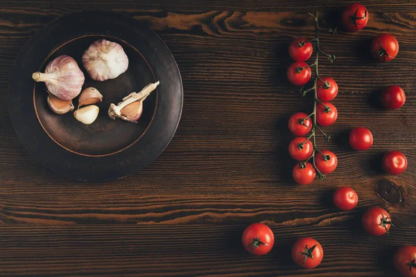 Teller mit Knoblauch und Kirschtomaten — Stockfoto