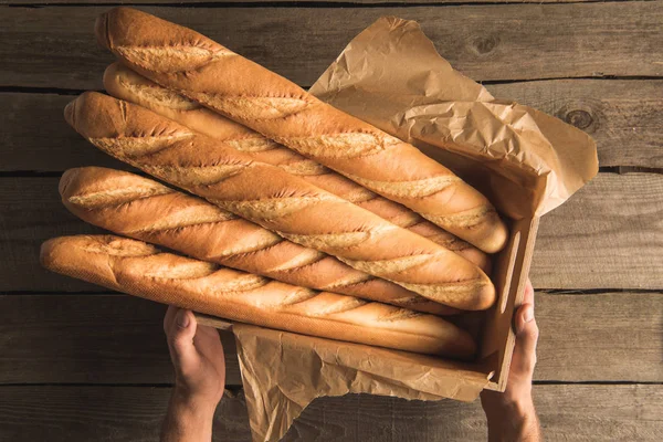 Hände halten Box mit Baguette — Stockfoto