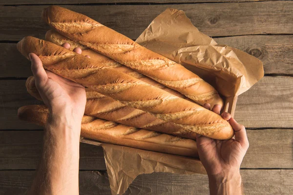 Hands holding box with baguettes — Stock Photo, Image