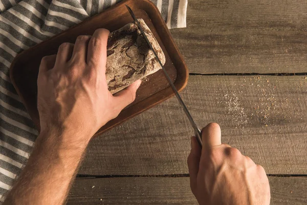 Hands cutting loaf of bread — Stock Photo, Image